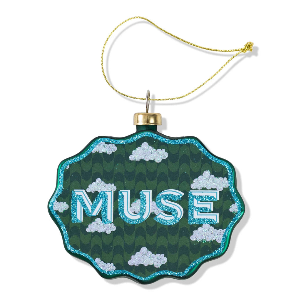 Decorative glass ornament with scalloped edge and 'muse' text on a white background.