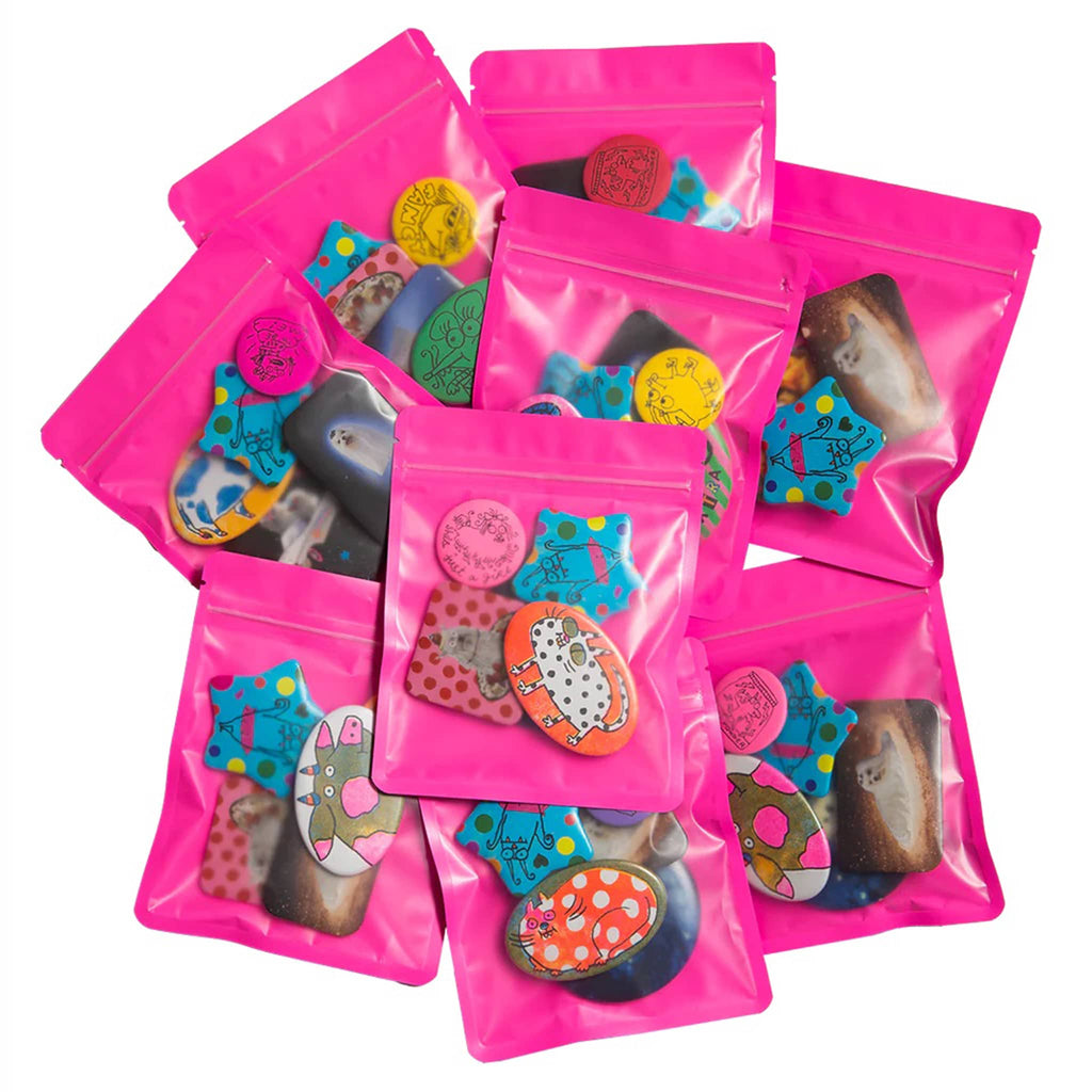 Collection of hot pink pouches filled with assorted colorful pinback buttons on a white background.