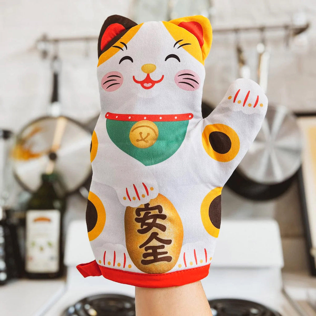 Fred Feline Lucky Oven Mitt shaped like a lucky waving cat (Maneki Neko), front view on hand in kitchen setting.