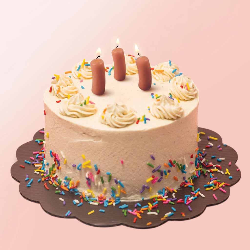 Birthday cake with cocktail weenie candles and sprinkles on a pink background.
