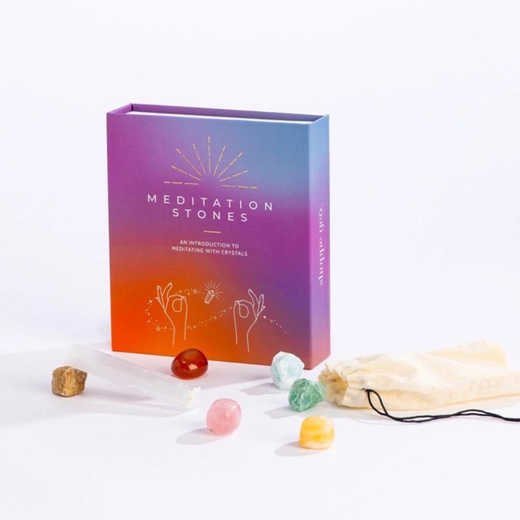 Geocentral Meditation Stones: An Introduction to Meditating with Crystals in orange, purple and blue ombre box packaging with drawstring bag and contents in front of the standing box.