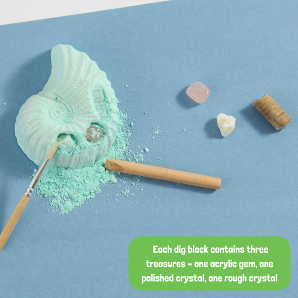 Toy excavation set with shell, brush, and crystals on a blue background.