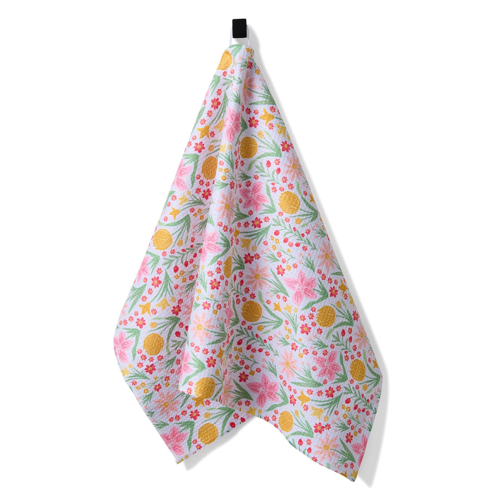 Geometry Garden of Light eco-friendly kitchen tea towel with a pink, green and yellow floral print, hanging from attached loop.