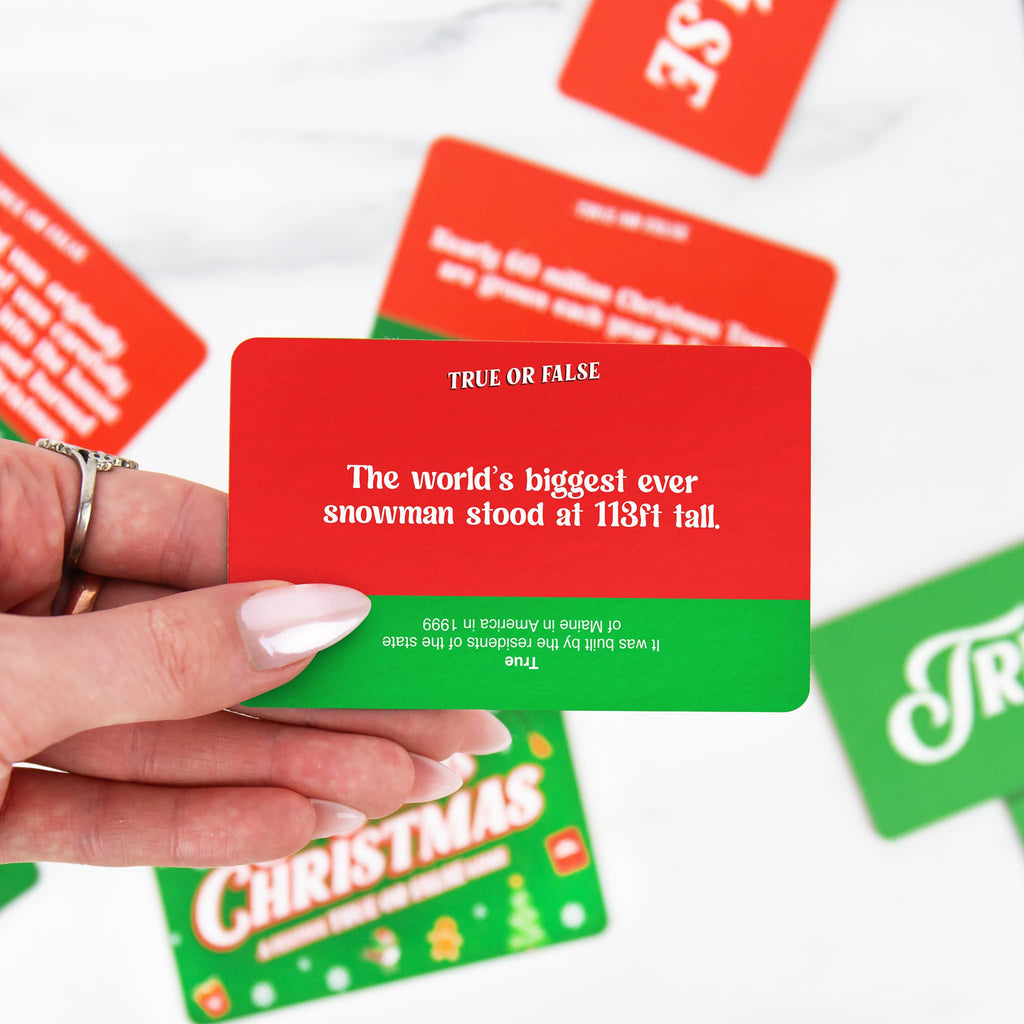 Hand holding a red and green card with a trivia question, surrounded by more cards on a white background.