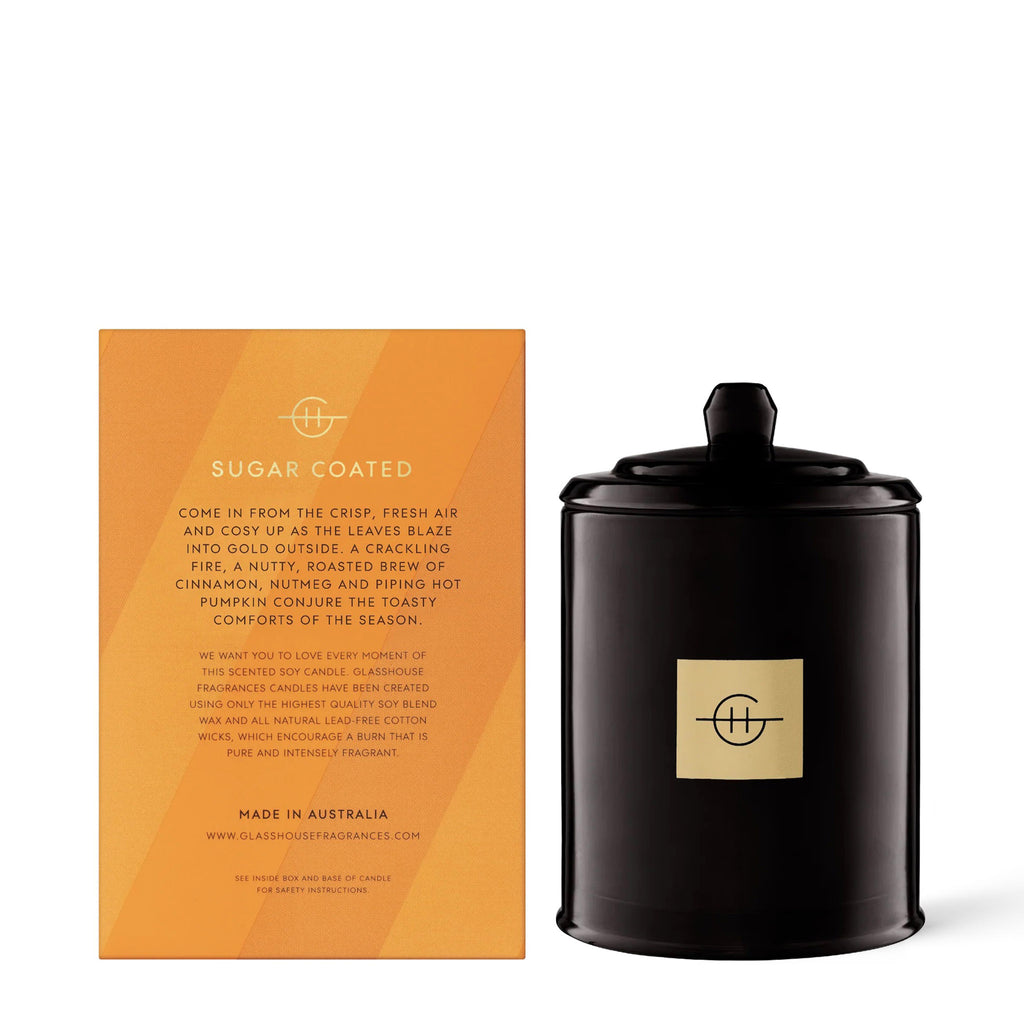 Glasshouse Fragrances In Season Pumpkin Spiced Cake scented soy wax candle in glossy black glass jar with lid beside orange striped gift box, back view.