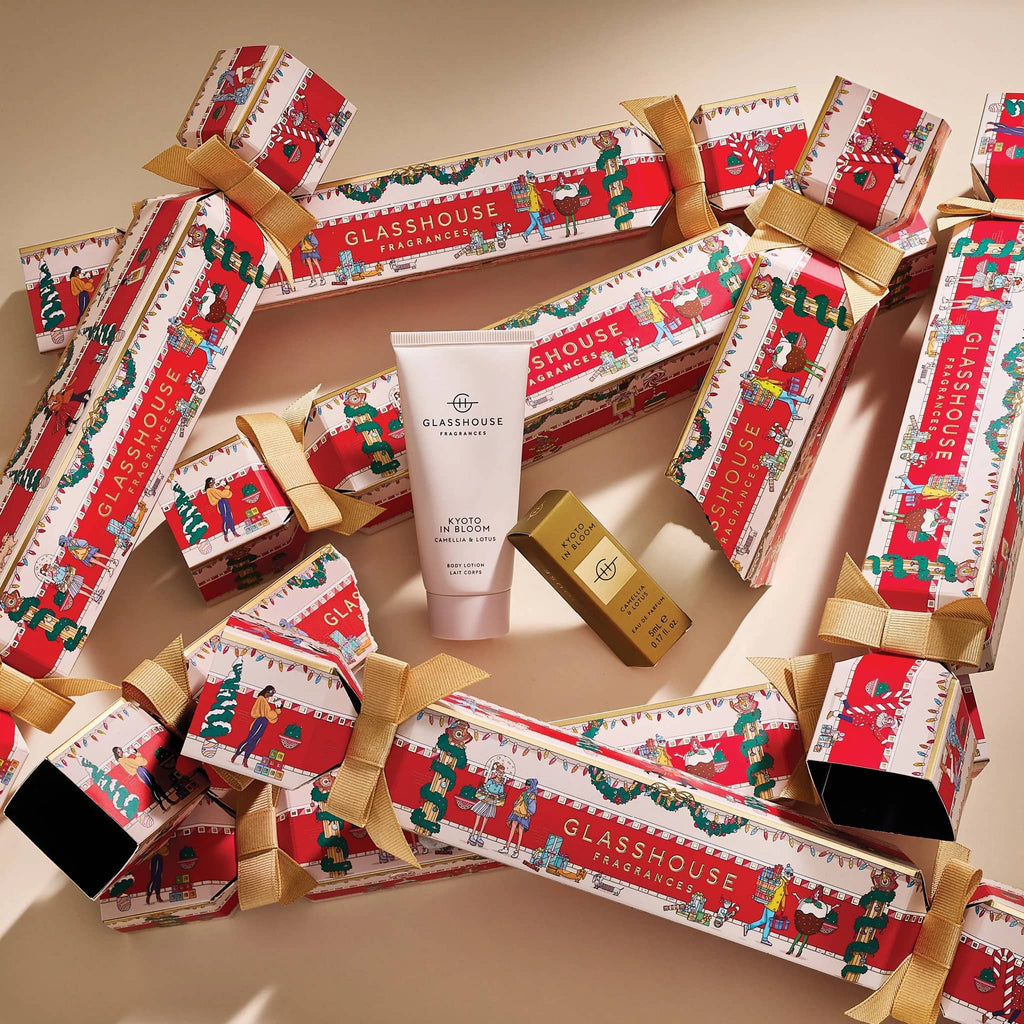 Glasshouse travel body lotion and eau de parfum with festive holiday cracker packaging on a beige background.
