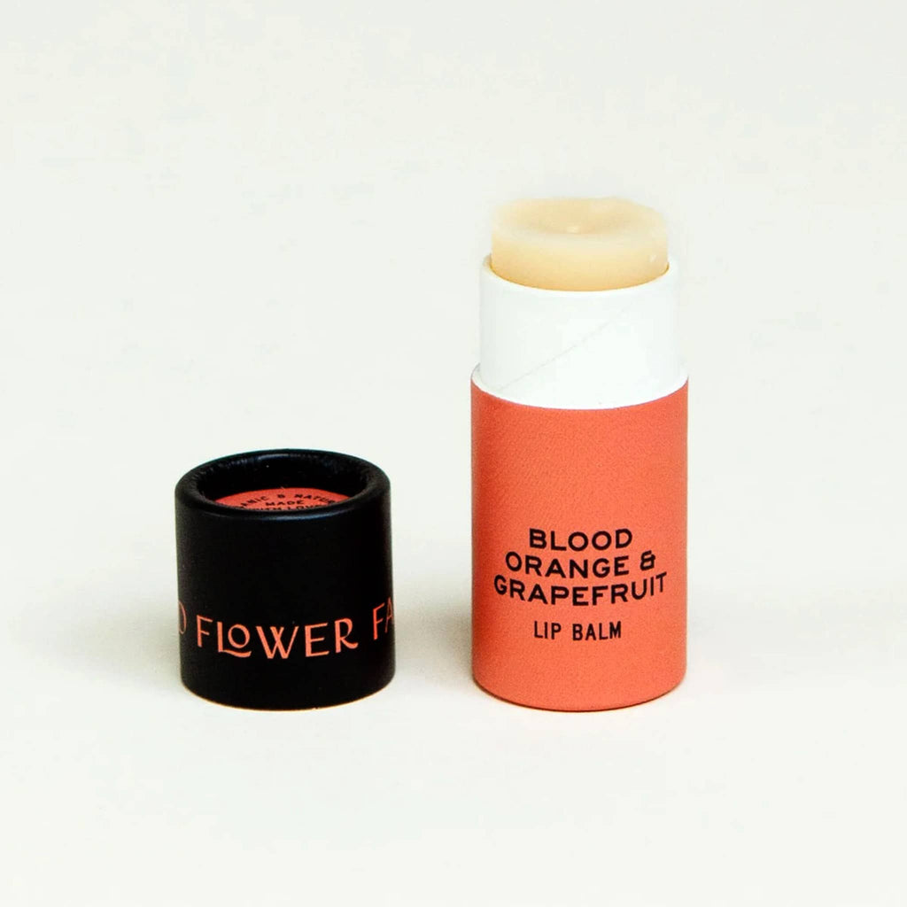 Good Flower Farm Blood Orange and Grapefruit scented lip balm in orange paper tube packaging with lid off.