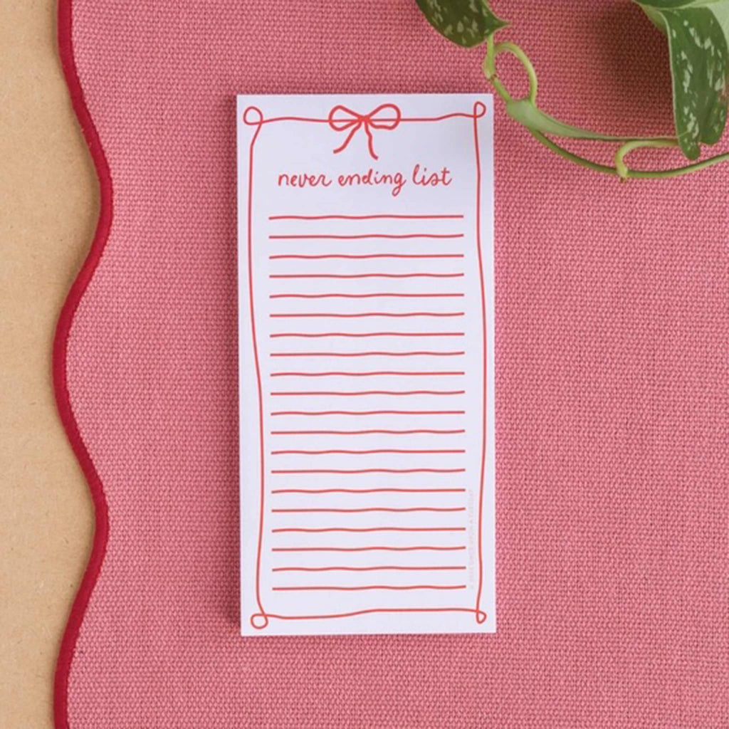 Notepad with 'never ending list' text on a pink surface.