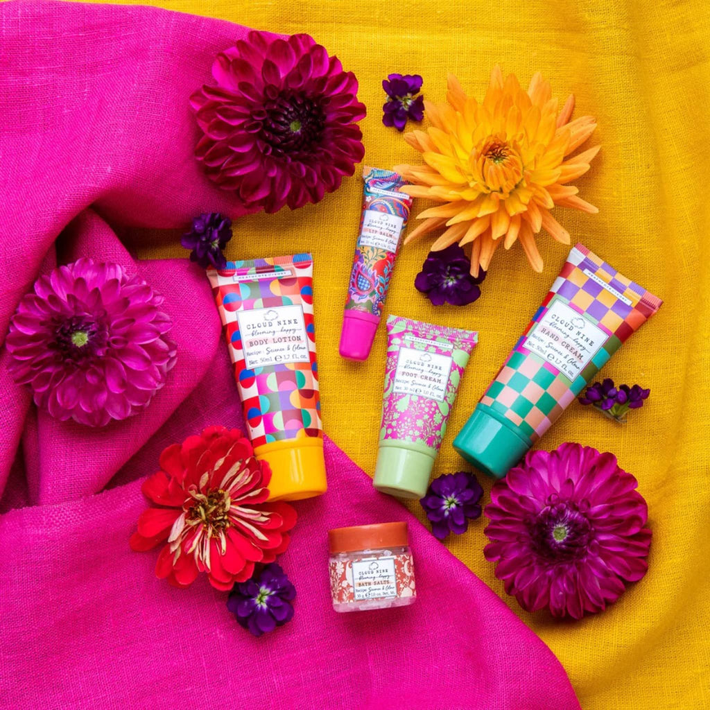 Heathcote & Ivory Cloud Nine Blooming Happy Top to Toe beauty kit, contents on pink and yellow fabric backdrop with flowers.