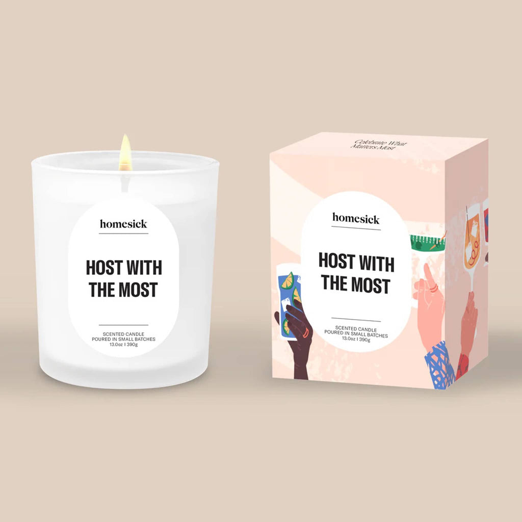 Homesick 'Host with the Most" candle and pink illustrated box packaging on a beige background.