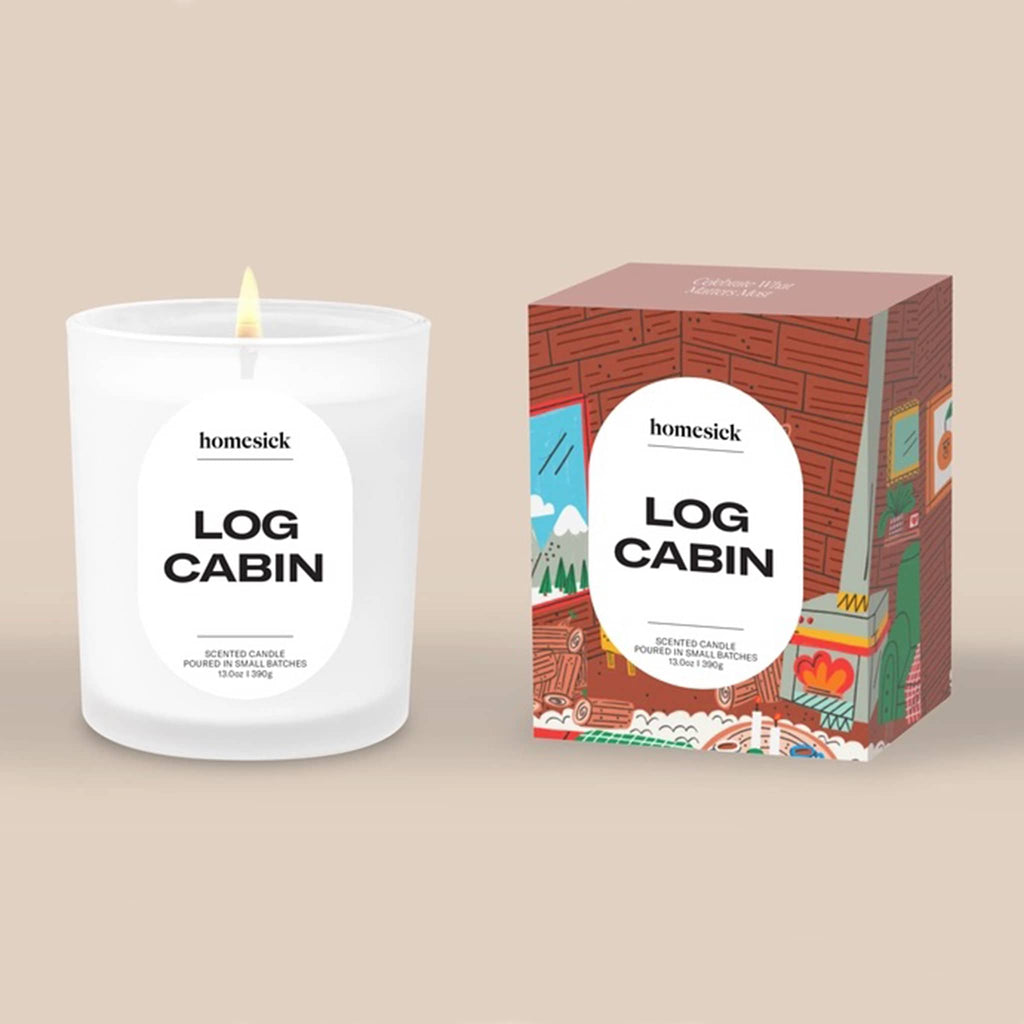Homesick Log Cabin candle and illustrated box packaging on a beige background.