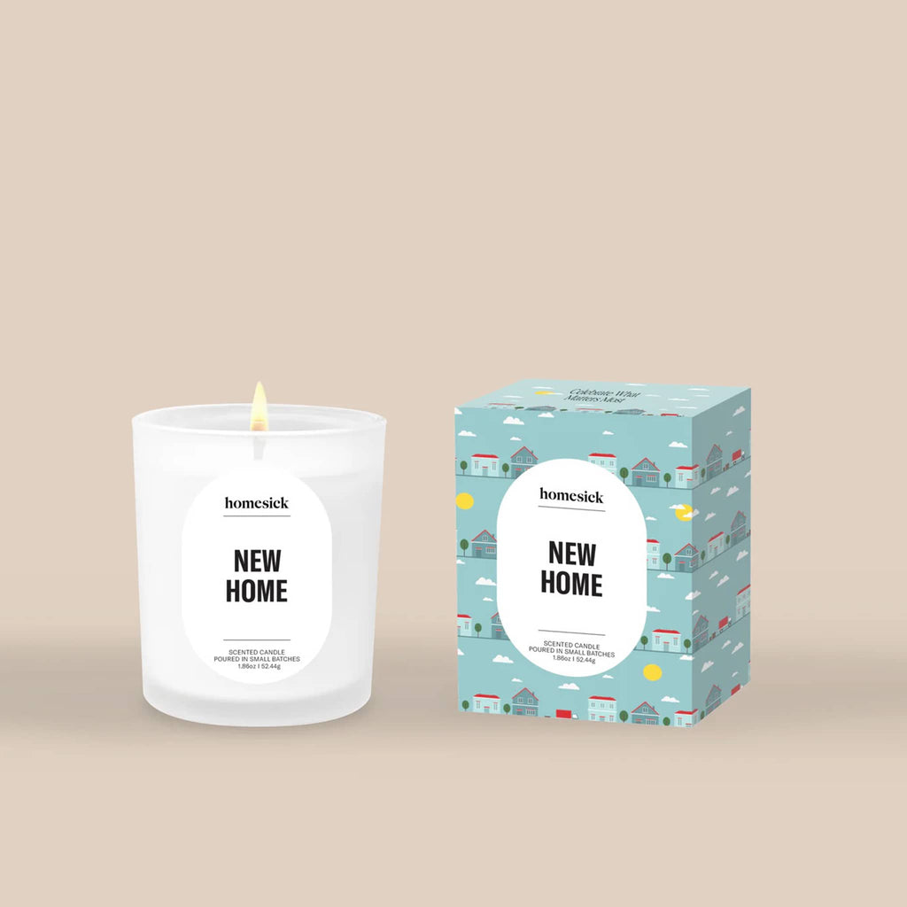 Homesick 'New Home' mini candle with illustrated blue box packaging on a beige background.