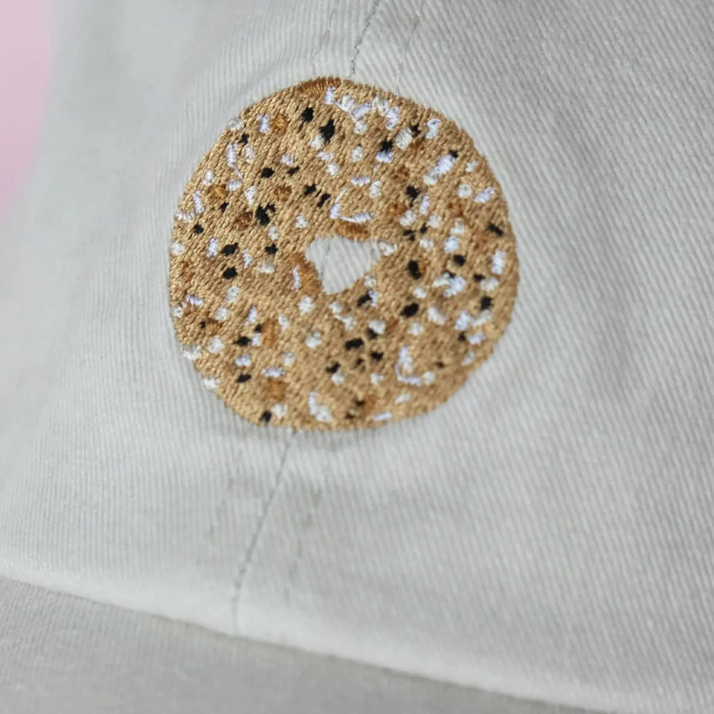 Close-up of everything bagel embroidery on a light khaki fabric background.