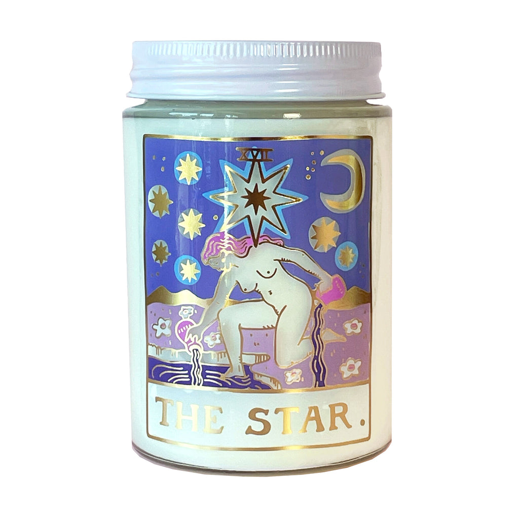 Idlewild Co. x Botanica Candle The Star Tarot Candle with scented soy wax in clear glass jar with white aluminum lid and a tarot design illustration in blue, purple and gold foil on the front.