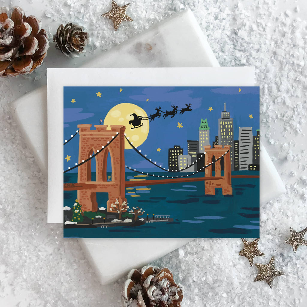 Christmas card with Santa Claus on a sleigh over a cityscape with a bridge, surrounded by decorative elements.