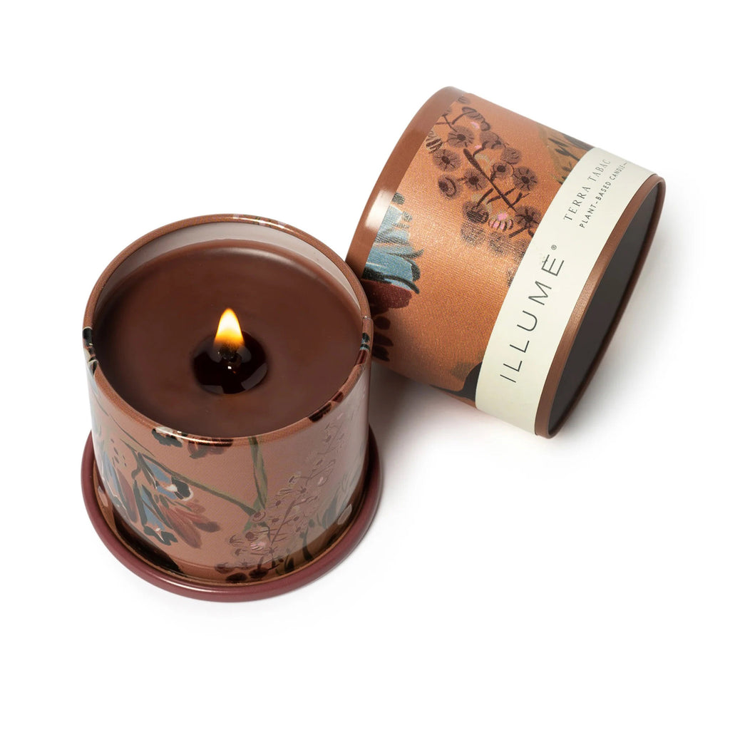 Illume Terra Tabac scented plant based wax candle in demi vanity tin, overhead view with lid off and candle lit.