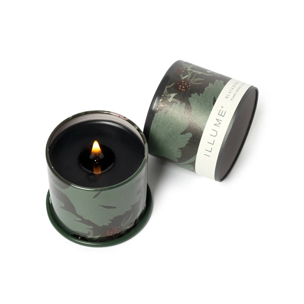 Dark green wax candle in a green tin with blackberry illustrations and 'ILLUME' branding on a white background.