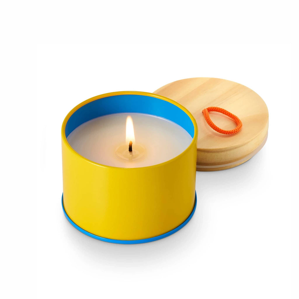 Illume Pool Floatie scented soy wax candle in yellow sun tin with wood lid off and wick lit.