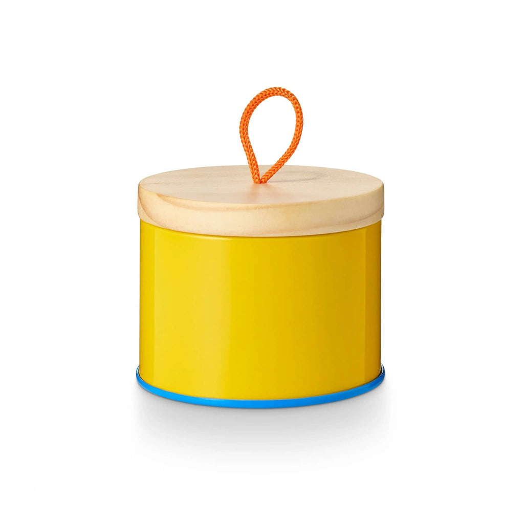 Illume Pool Floatie scented soy wax candle in yellow sun tin with wood lid on.