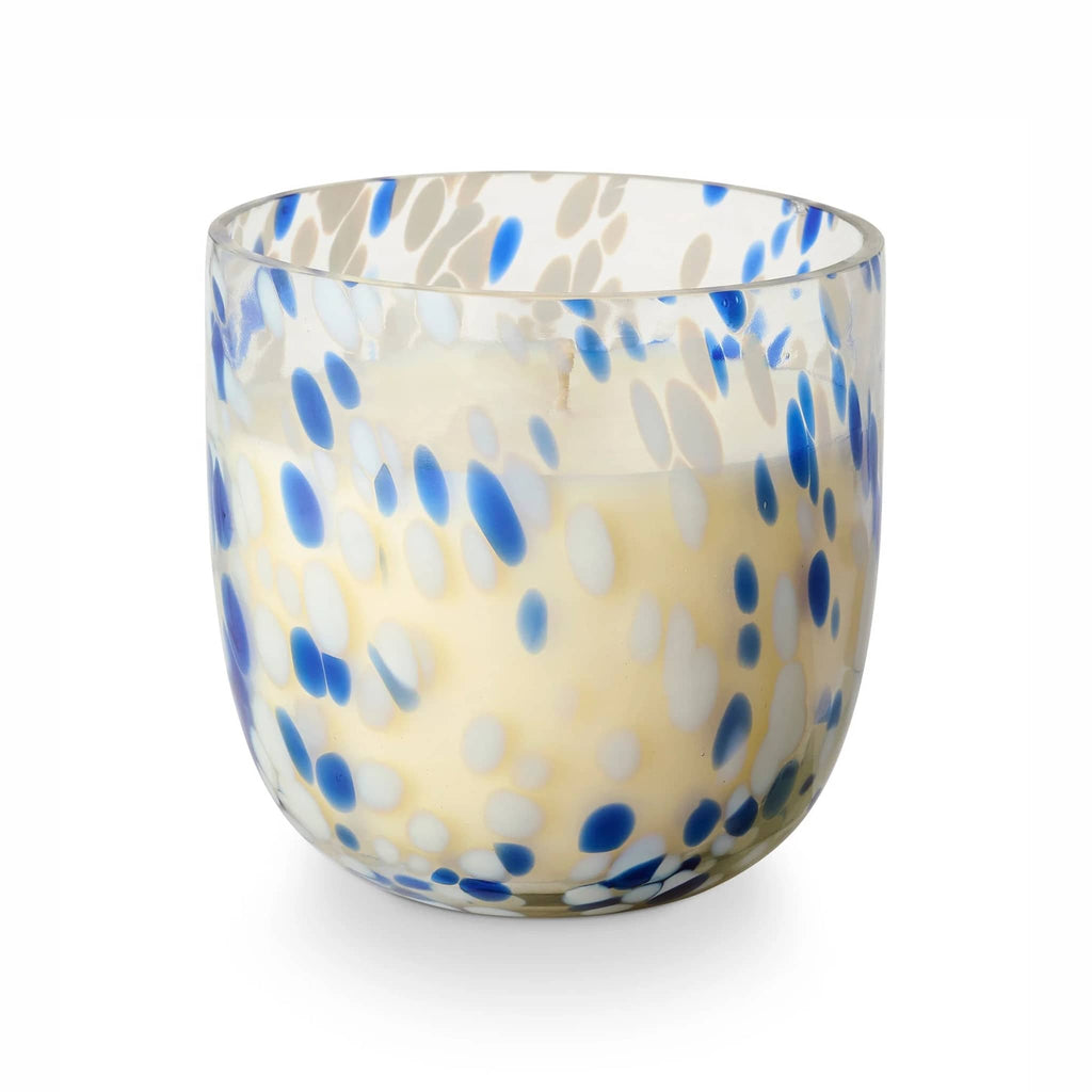 Illume Beach Towel scented soy wax candle in blue and white speckled sun glass vessel, front view.