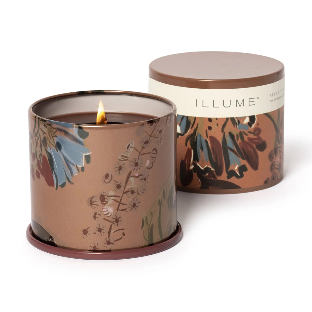 Illume Terra Tabac scented plant based wax candle in large vanity tin, front view with lid off and wick lit.