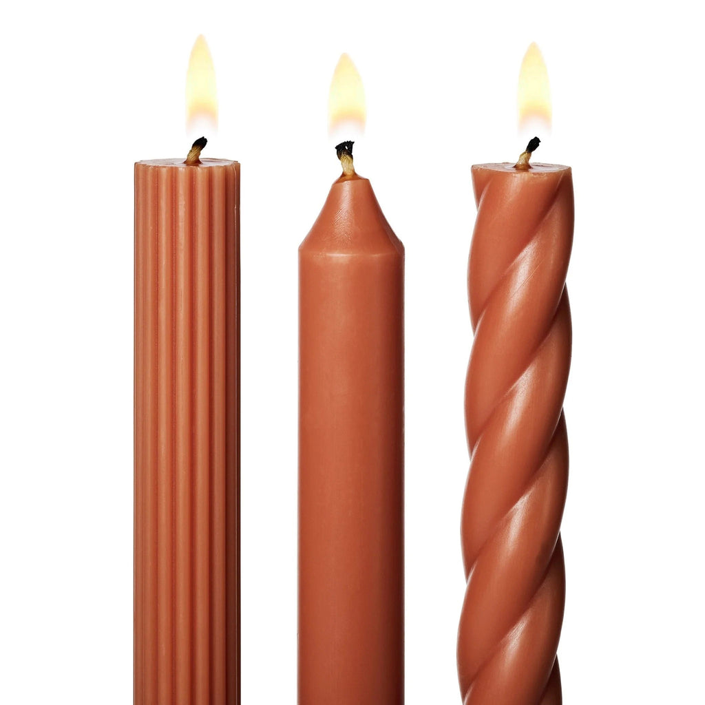 Illume Terracotta Burnt Orange Set of 3 taper candles in assorted textures, detail of wick, lit.