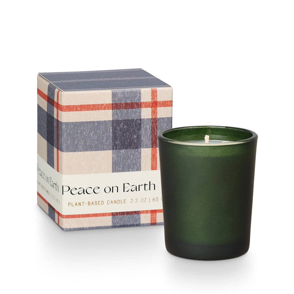 Illume Balsam & Cedar holiday scented votive candle in matte green glass vessel with blue, red and ivory plaid gift box with "peace on earth" on the label.