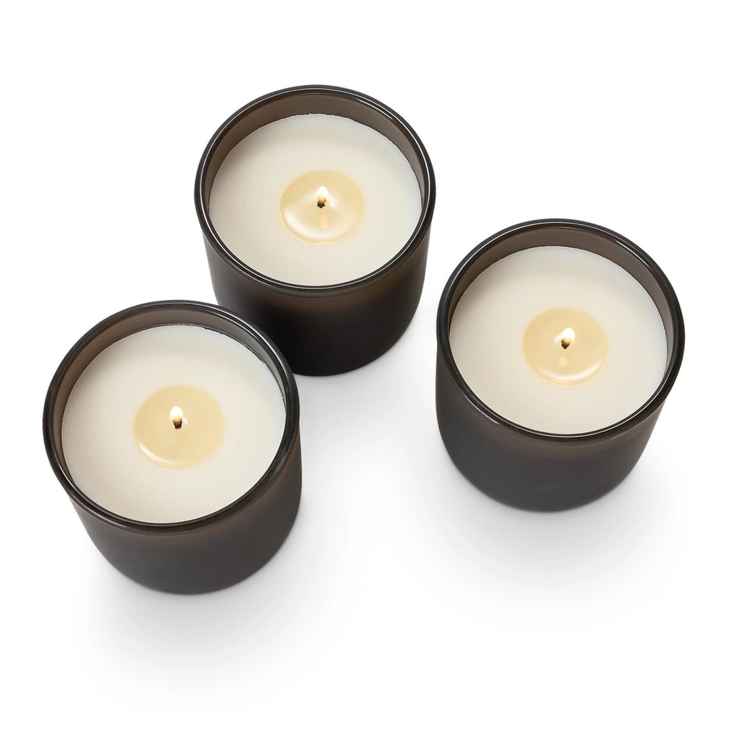 Illume Woodfire Candle Trio Gift Set, 3 candles in matte brown glass vessels, all with wicks lit.