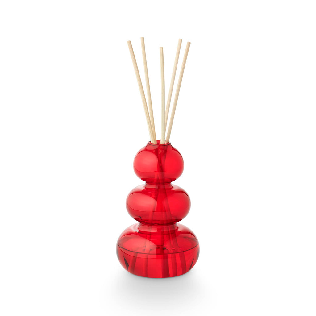 Illume Memory Lane Mistletoe Kisses scented holiday diffuser in red bubble glass vessel with natural reeds.