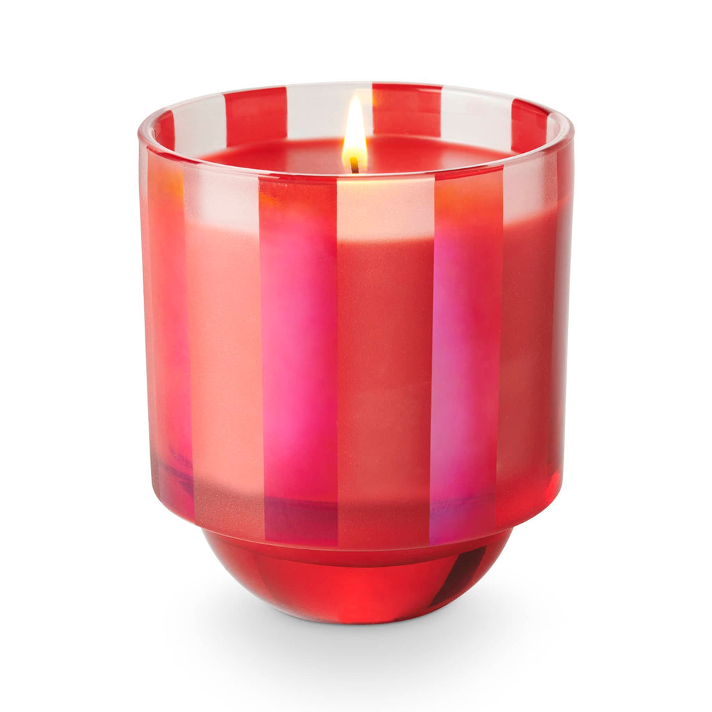 Illume Memory Lane Mistletoe Kisses holiday scented soy wax candle in matte clear and pink striped glass vessel, wick lit.