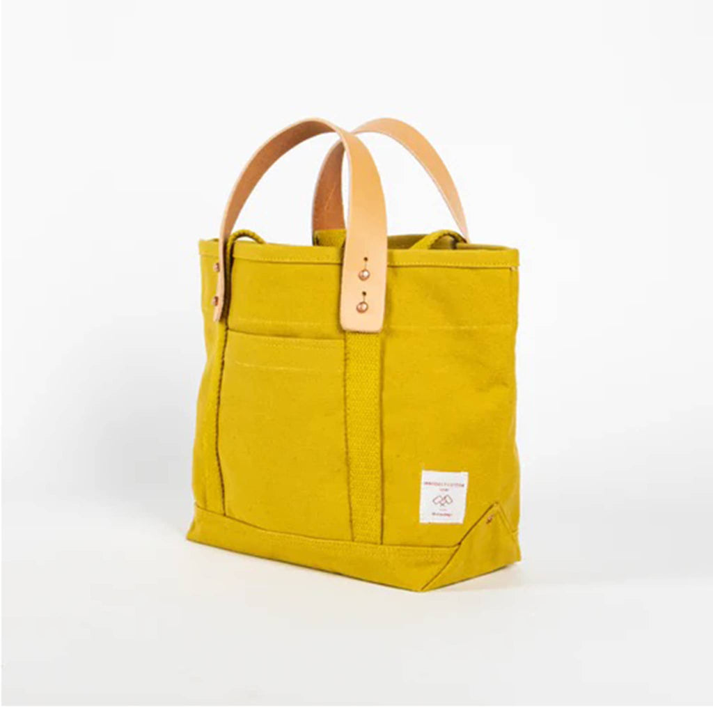 Chartreuse canvas tote bag with removable leather handles, front angle view, on a white background.