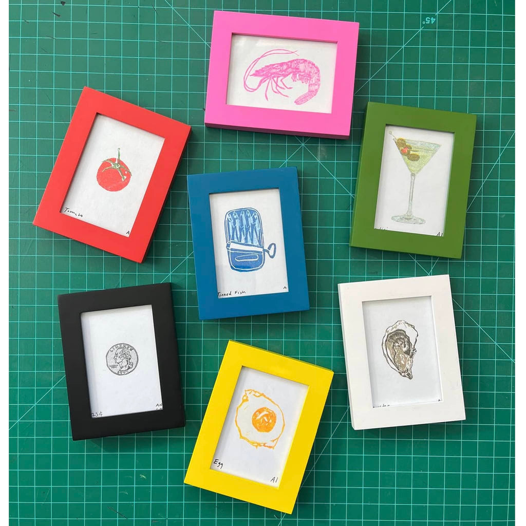 Set of 7 colorful picture frames with prints on a green cutting mat.