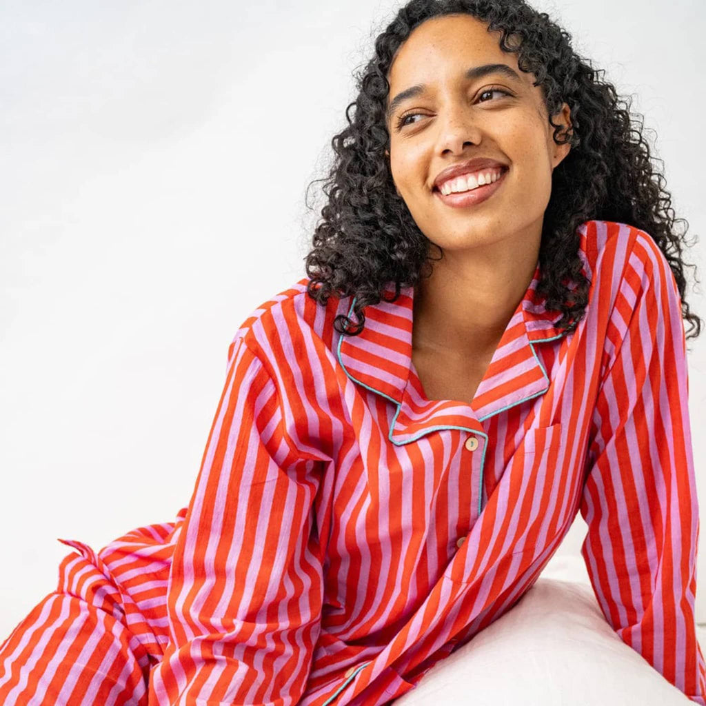 Woman wearing red and lilac striped pajama set on a white background.