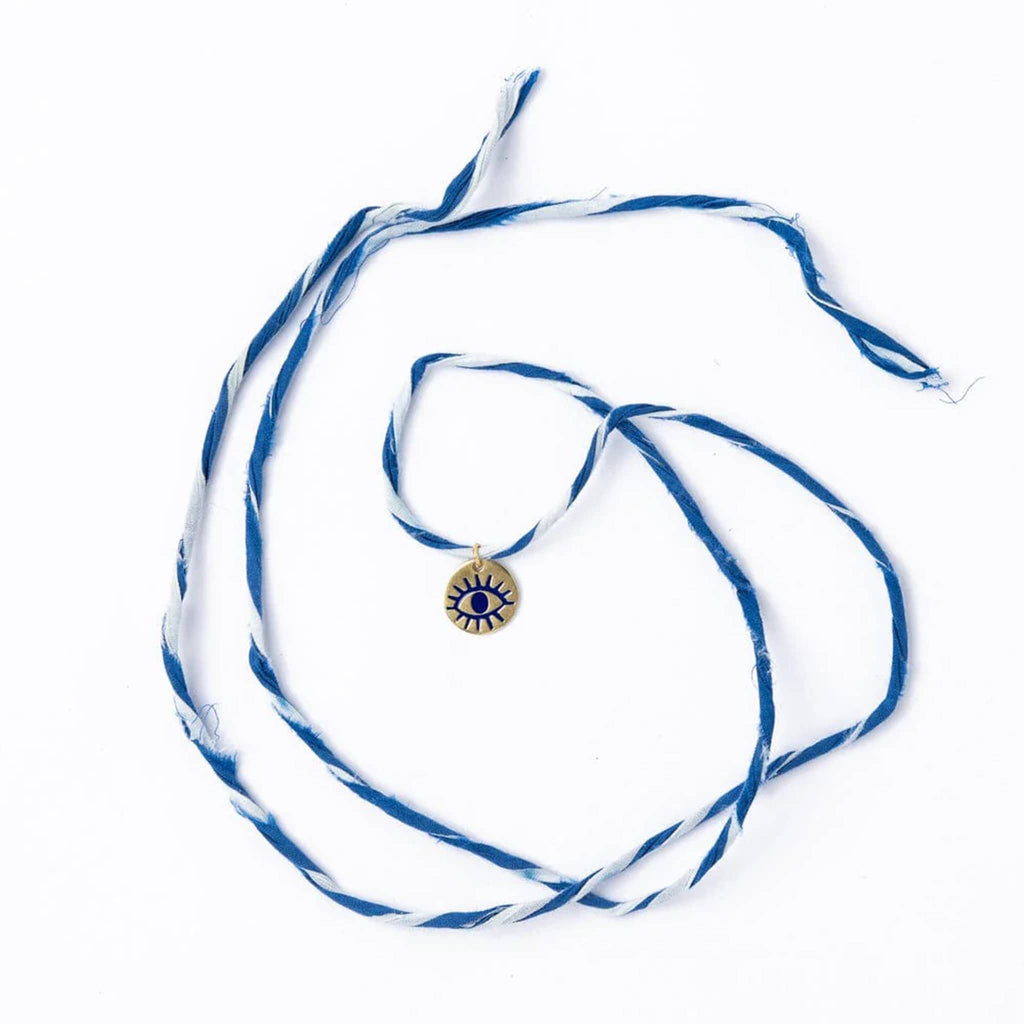Bracelet with blue and white twisted cord and brass eye charm on a white background.