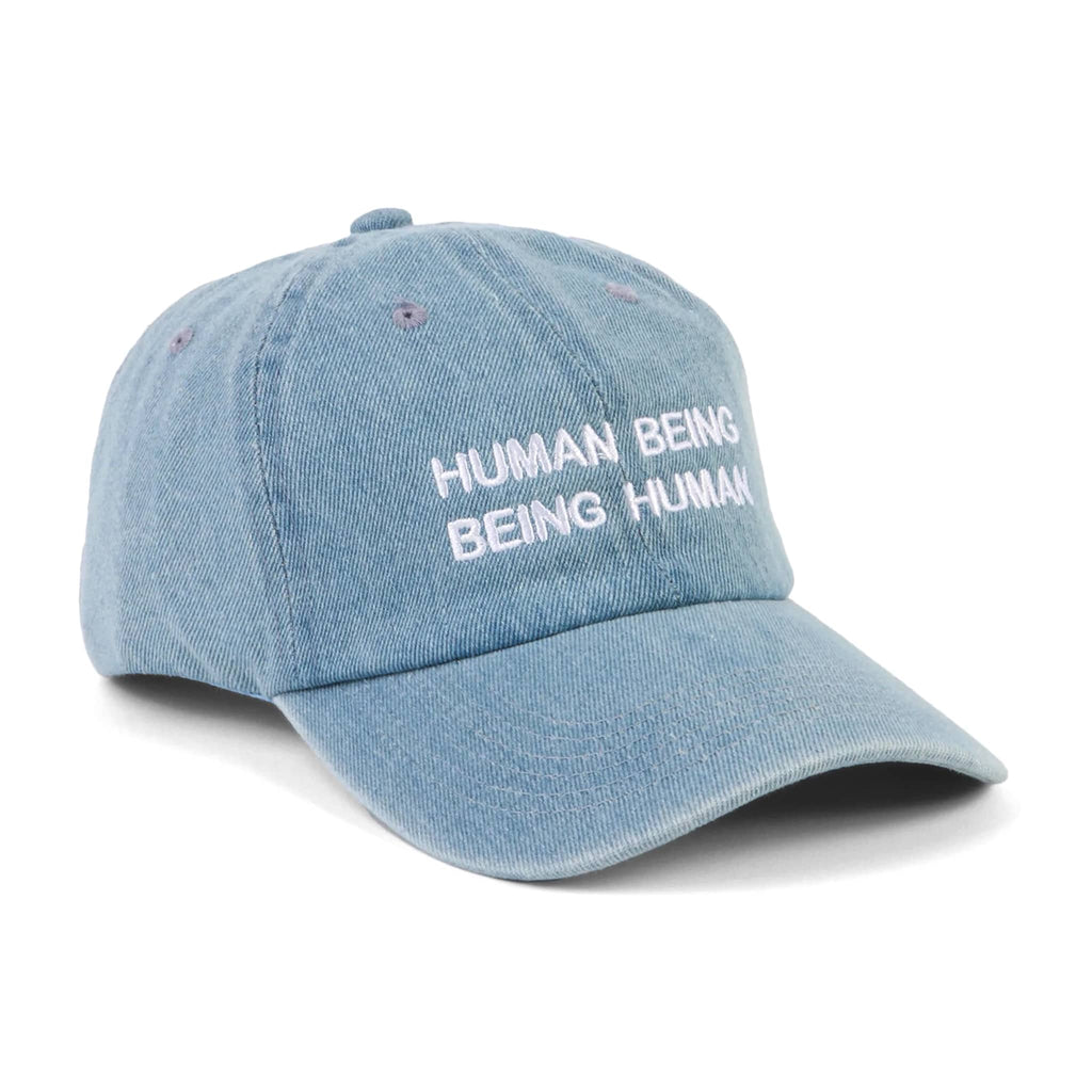Light blue denim cap with 'HUMAN BEING BEING HUMAN' text on a white background.