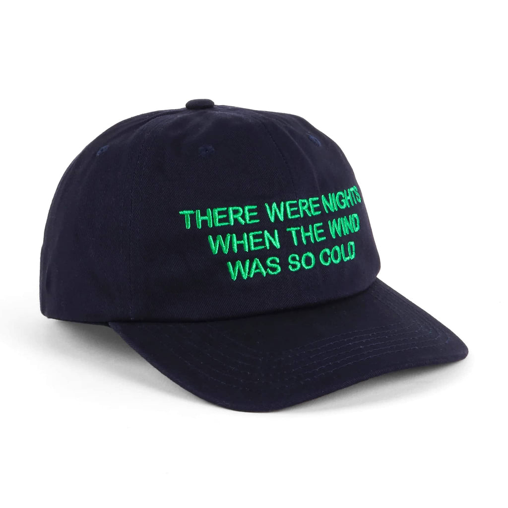 Navy ball cap with "there were nights when the wind was so cold" in green embroidered lettering, on a white background.