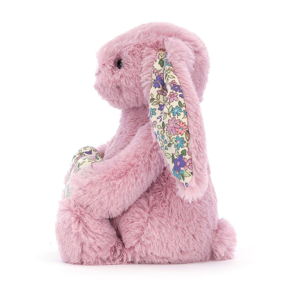 Jellycat Blossom Heart Tulip Pink Bunny plush toy holding a floral fabric heart with matching fabric in inner ears, side view.