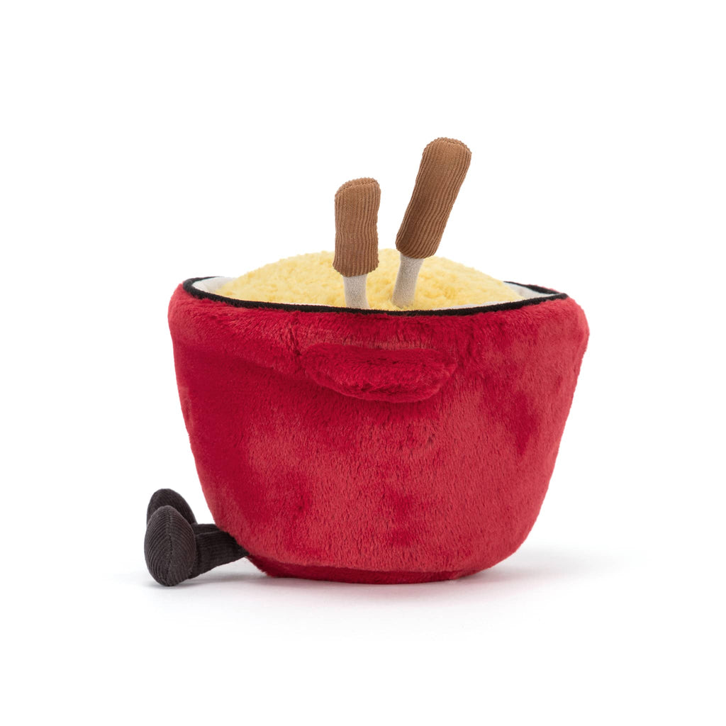Plush red cheese fondue pot with a smiling face and fondue forks, side view on a white background.