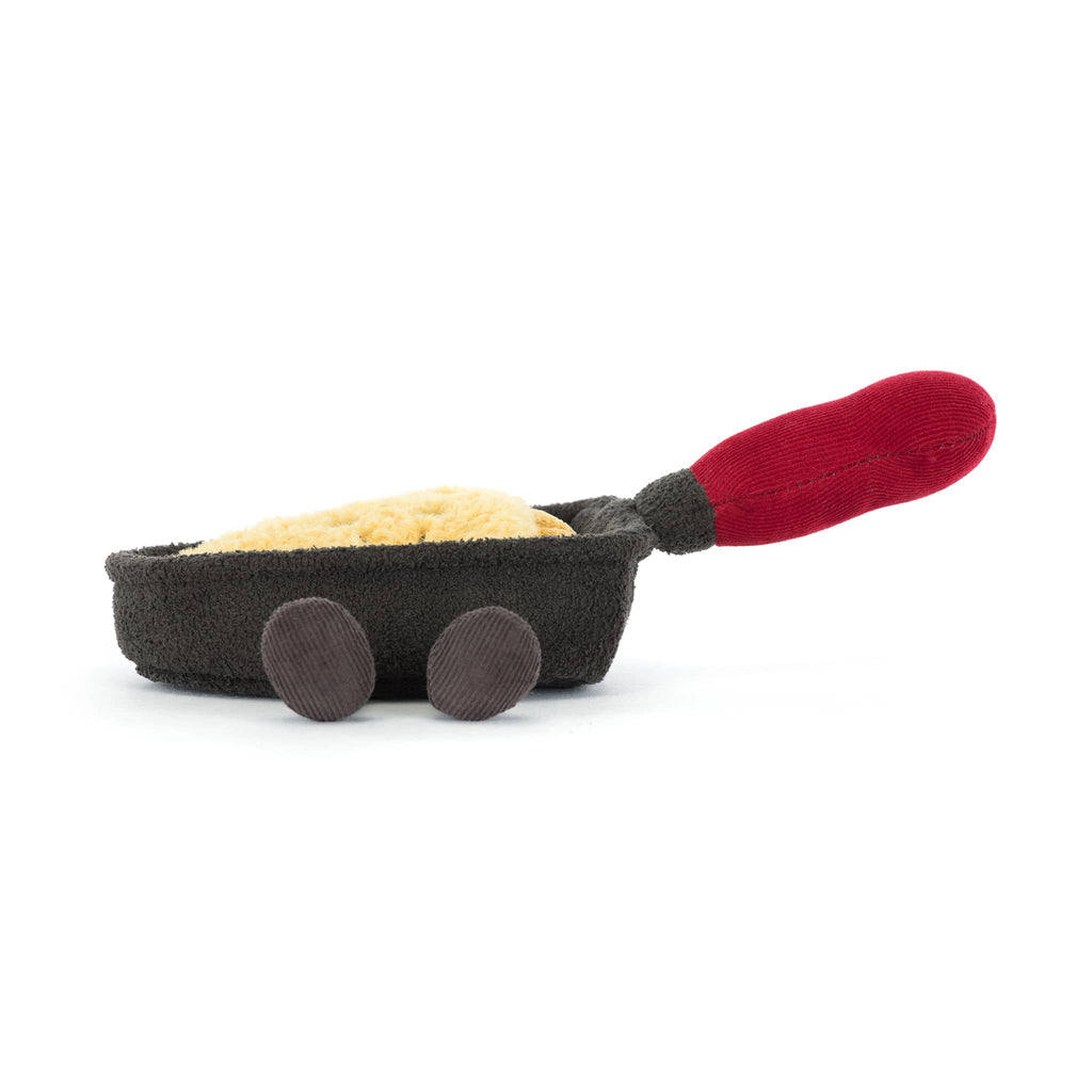 Plush brown raclette pan with smiling cheese inside and a red handle, front view on a white background.