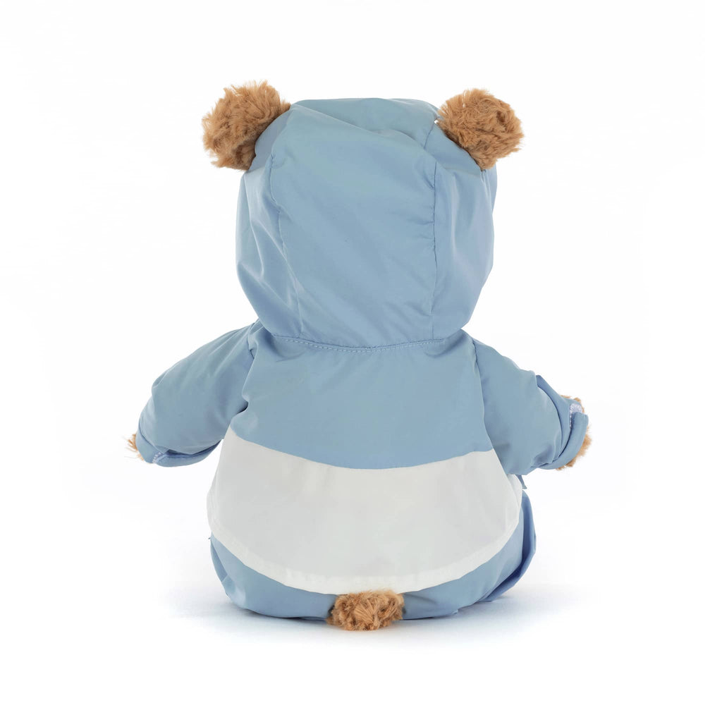 Plush teddy bear wearing a blue and white snowsuit, back view on a white background.