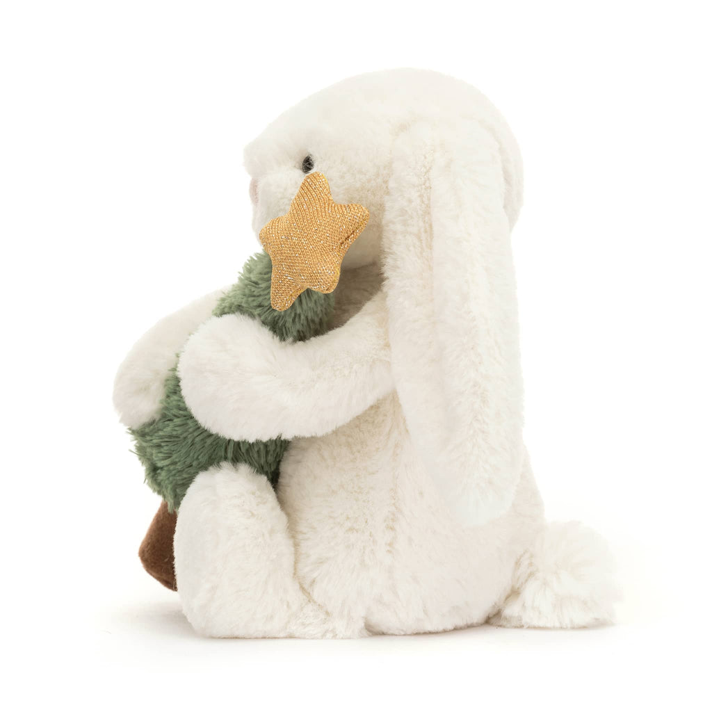 White plush bunny holding a green tree with a gold star on top, side view, on a white background.