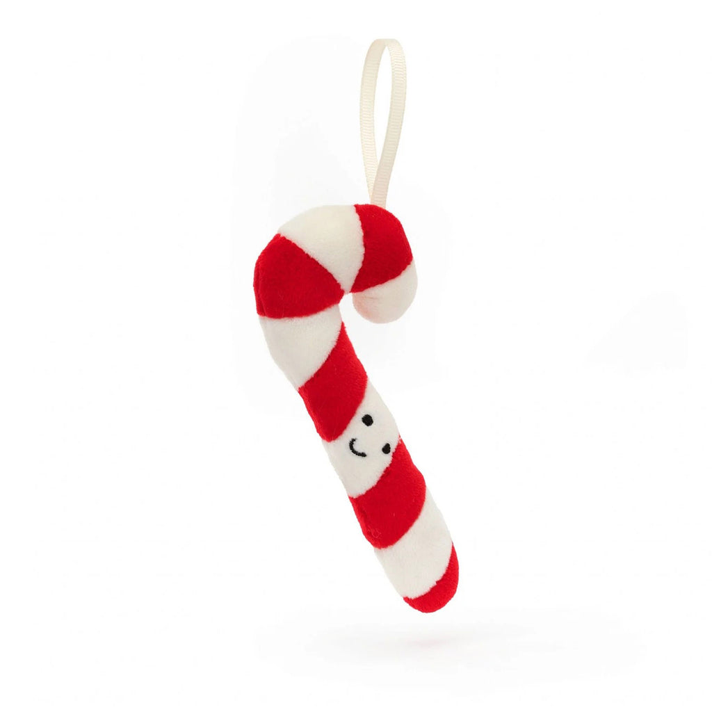 Jellycat Festive Folly Candy Cane Holiday Plush ornament, red and white striped cane shape with suede texture, black stitched eyes and mouth, white grosgrain ribbon for hanging, front view.