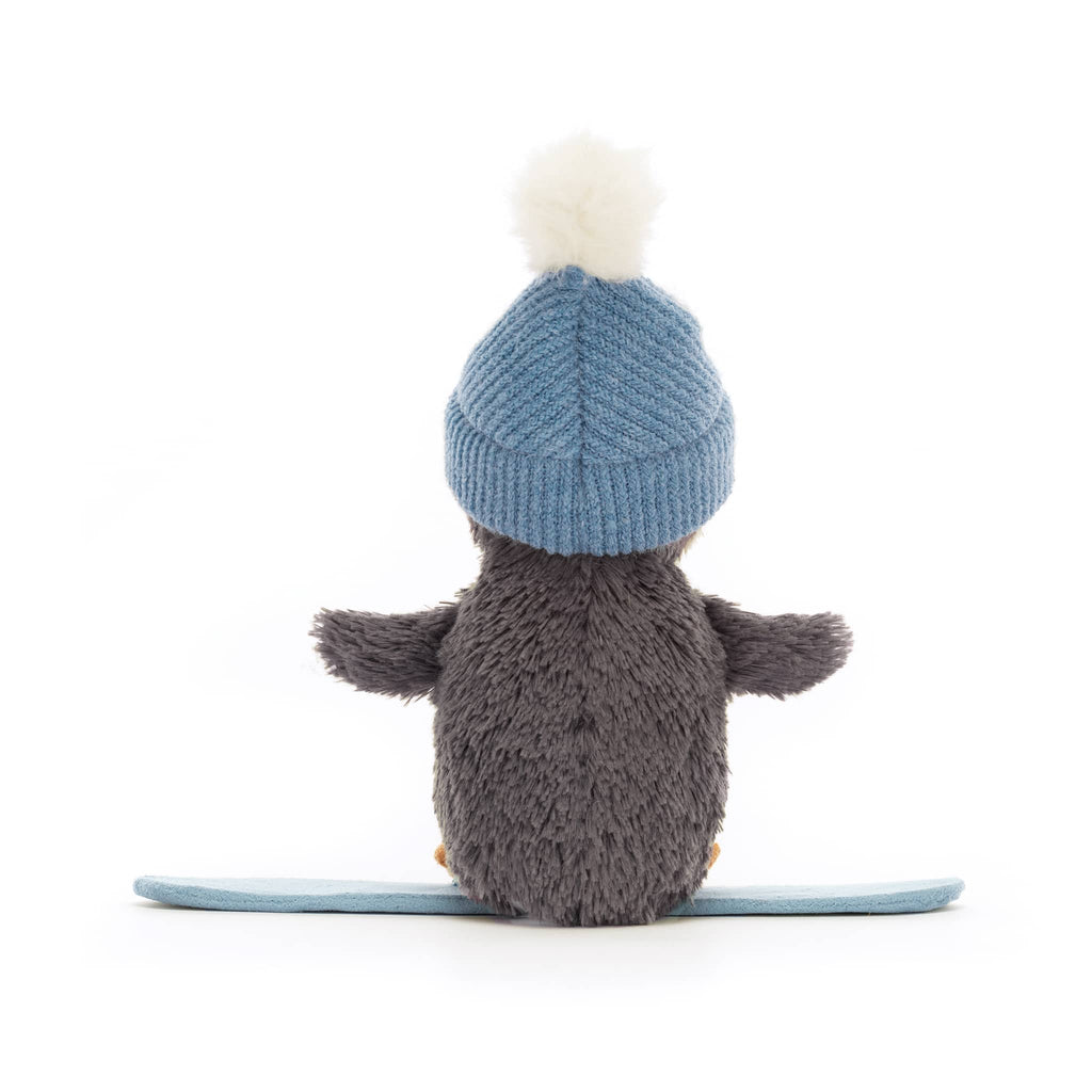 Stuffed animal penguin wearing a blue knitted hat from behind on a white background.