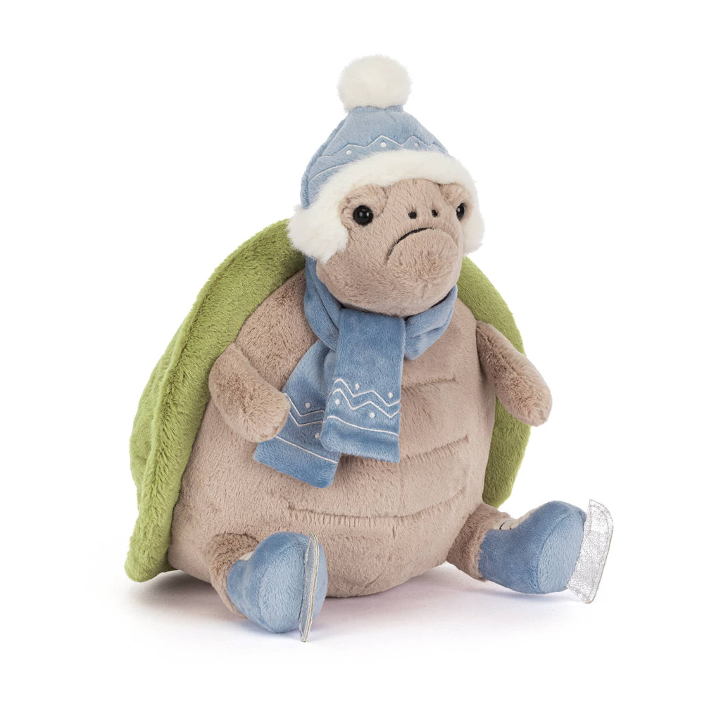 Plush turtle wearing a blue winter hat, scarf, and ice skates, front angle view on a white background.