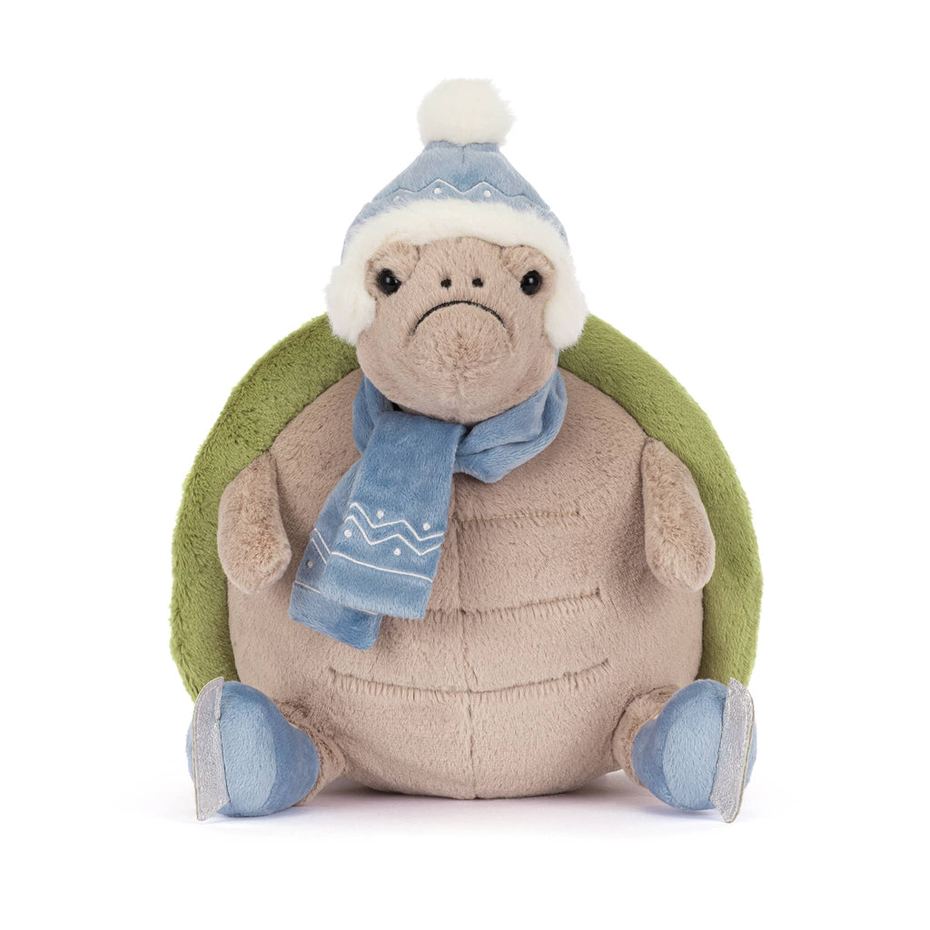 Plush turtle wearing a blue winter hat, scarf, and ice skates, front view on a white background.