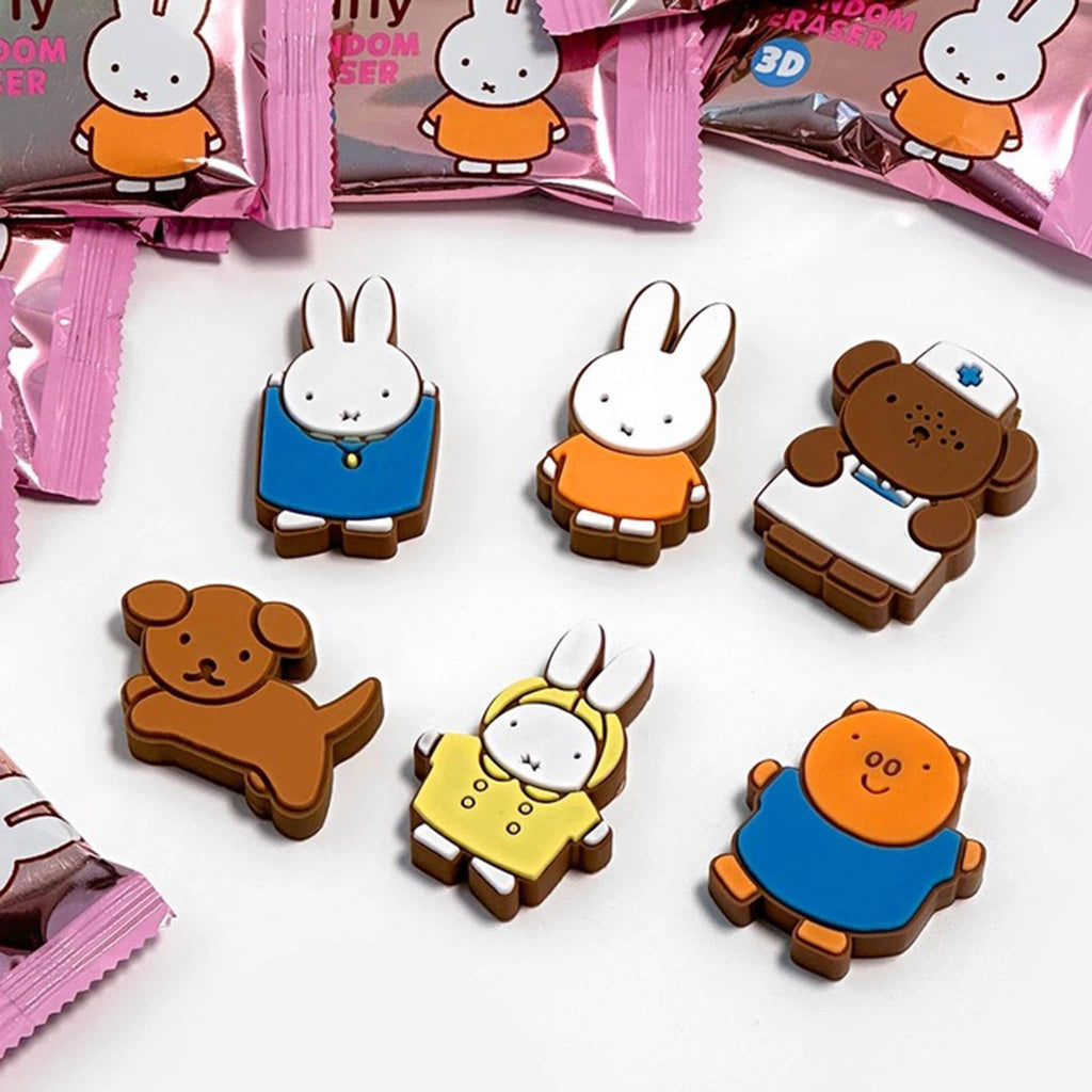 Cartoon character-shaped erasers on a white surface with pink packaging in the background.