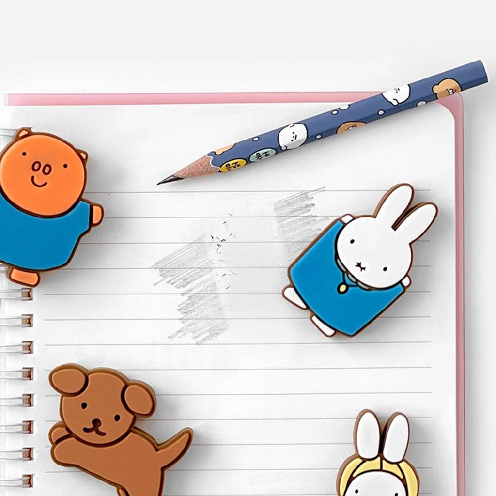 Notebook with cartoon character erasers and a pencil on a white background.