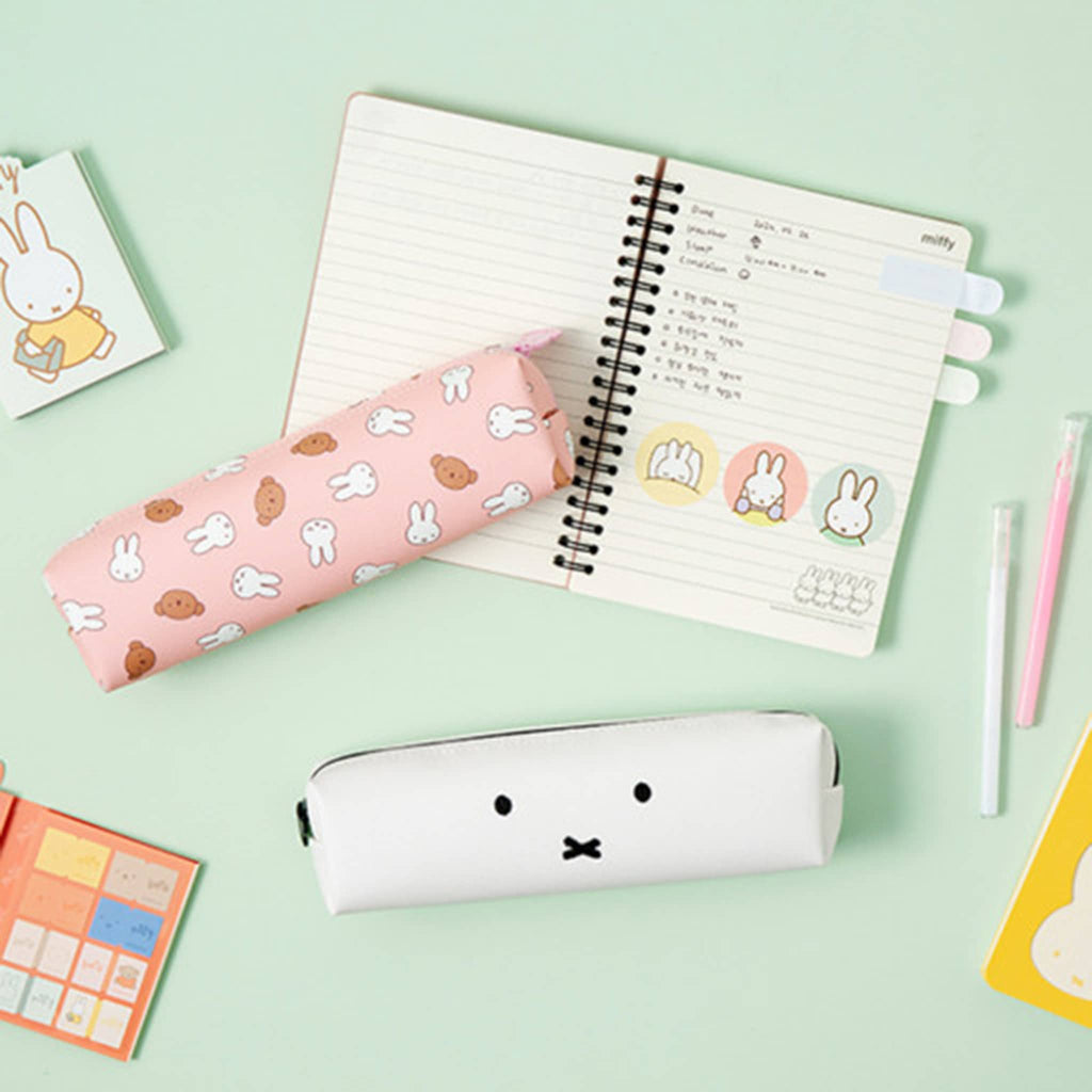 Two Miffy pencil cases on a light green background with a notebook and stationery items.