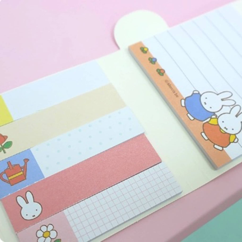Notebook with colorful pages and cartoon character on a pink background.