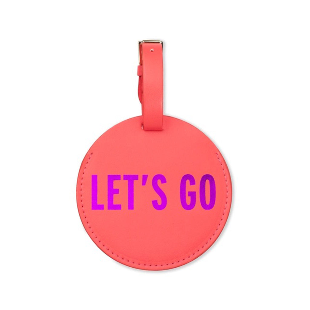 Kate Spade round red faux leather luggage tag with "let's go" in purple foil lettering and adjustable buckle strap, front view.